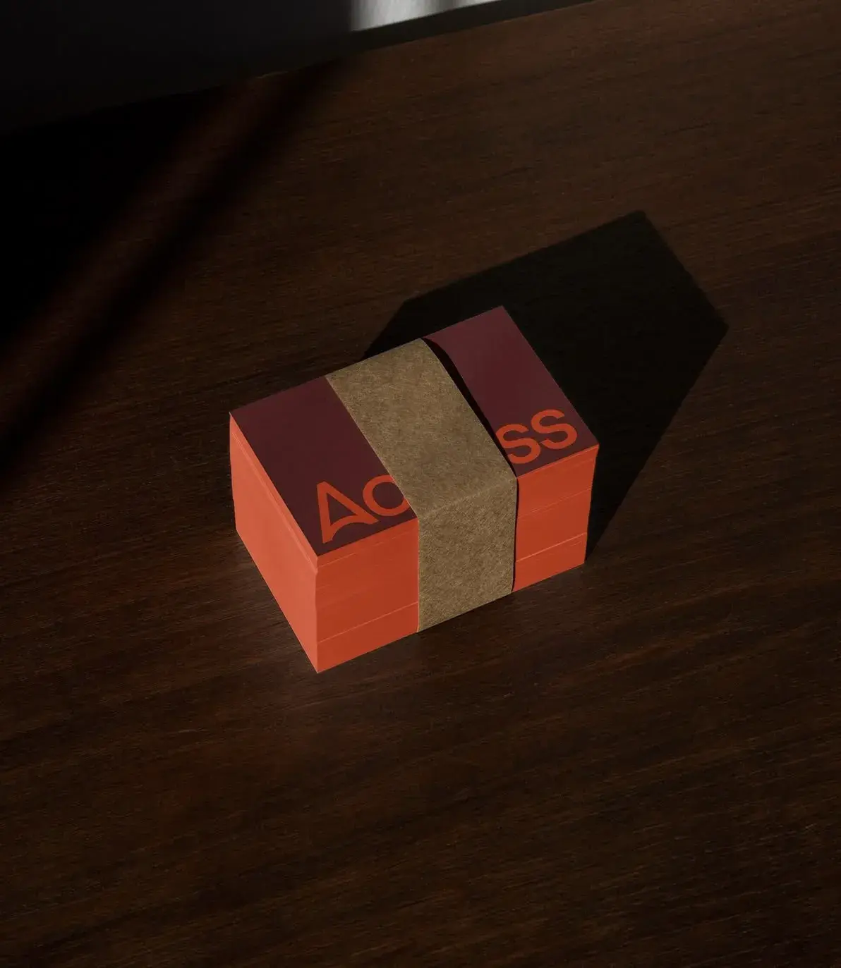 A stack of red-and-burgundy cards with the word "ACCESS" in orange, wrapped in a brown band, on a wooden table in sunlight.