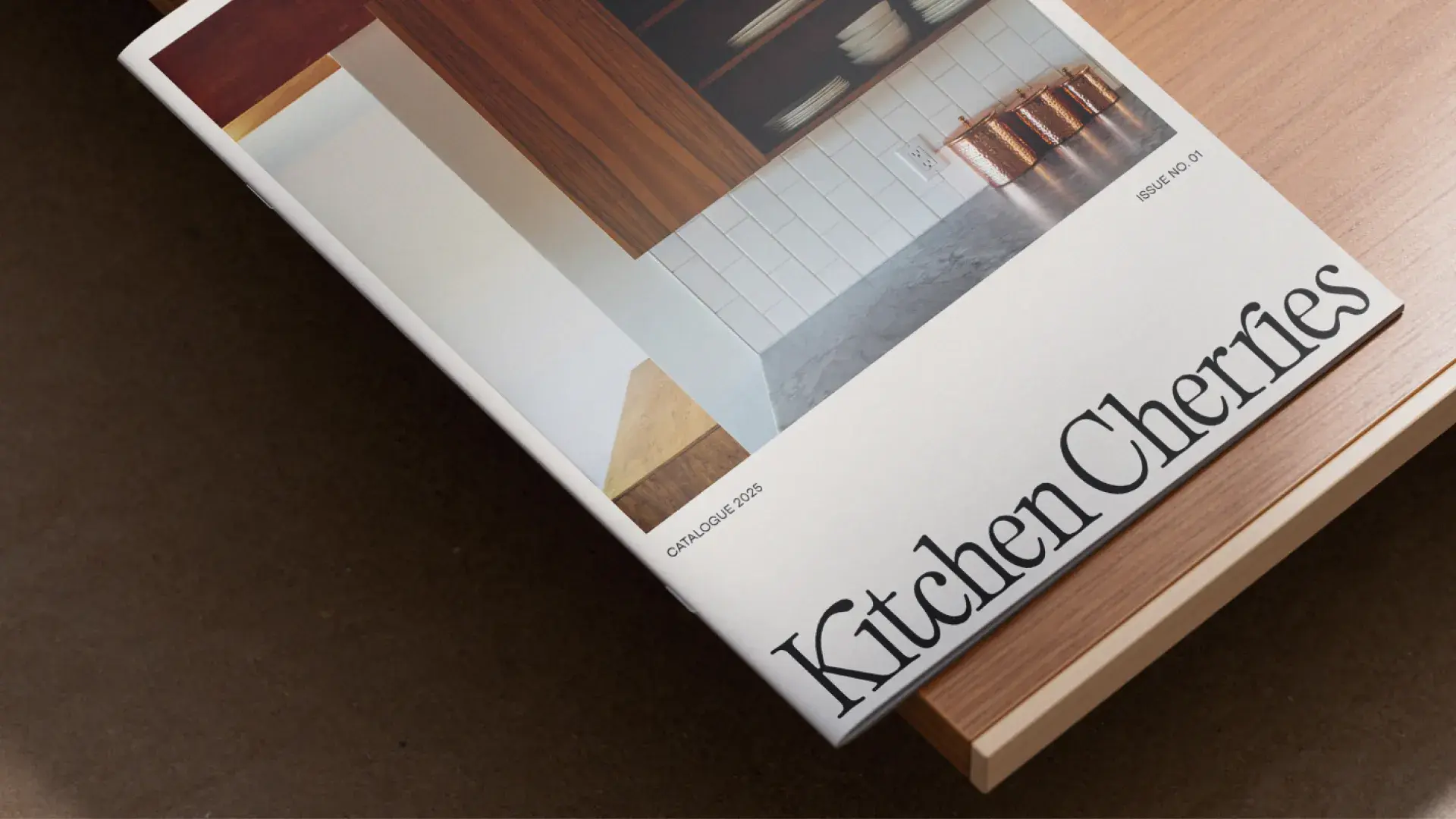 A catalog titled "Kitchen Chronicles" with a minimalist kitchen photo on the cover, resting on a wooden surface.