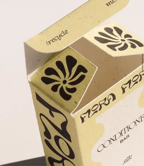 A partially open cardboard box with decorative black patterns and the word "recycle" visible on the inside flap.