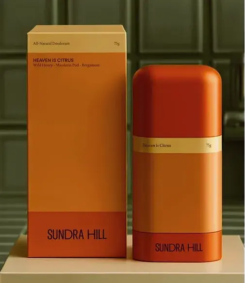 Orange and beige Sundra Hill deodorant packaging with "Heaven is Citrus" label, featuring wild honey, mandarin peel, and bergamot.