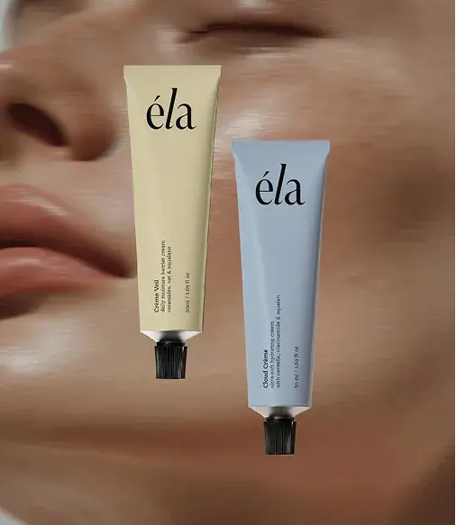 Two tubes of "éla" skincare cream, one beige and one blue, with black caps, against a blurred face background.